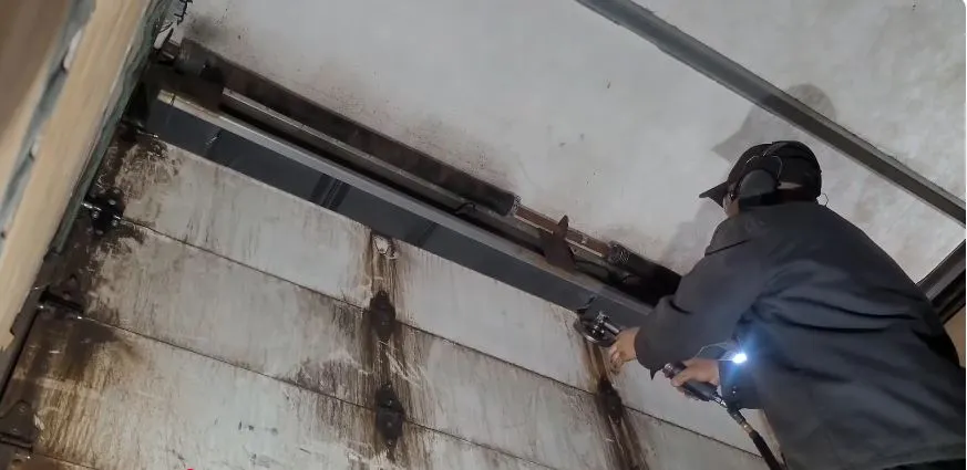 Technician working on the torsion shaft and track of a box truck roll-up cargo door